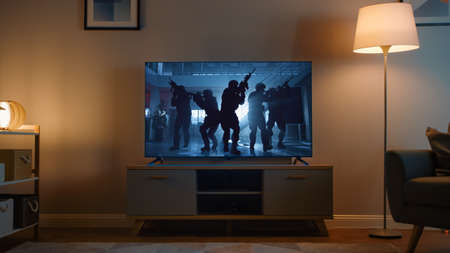 Shot of a TV with an Action Movie with Soldiers. Its Evening and Room at Home Has Working Lamps.の写真素材