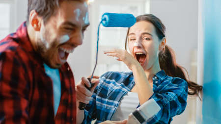 Young Beautiful Couple Decorate Their New Apartment and Fool Around. Husband and Wife are Painting...
