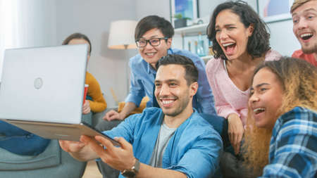Diverse Group of Friends Use Laptop in the Living Room. Happy Beautiful Girls and Guys Doing Live...