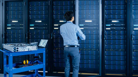 In the Modern Data Center: IT Engineer Doing Maintenance and Diagnostics. Works with Opened Cabinet...