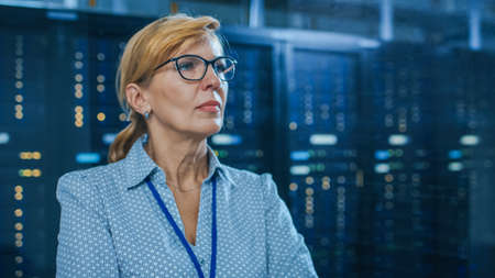 Portrait of a Beautiful Senior Female IT Technician Standing In Modern Data Center. In the...