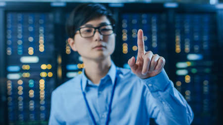 In the Modern Data Center: Portrait of Asian IT Engineer Working With Touch Screen Device, Doing...