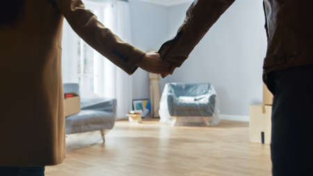 Excited Young Couple Holding Hands Enters Newly Purchased / Rented Apartment. Bright Modern Home for...