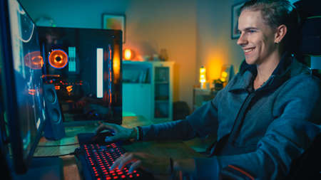 Happy Gamer Playing First-Person Shooter Online Video Game on His Powerful Personal Computer. Room...