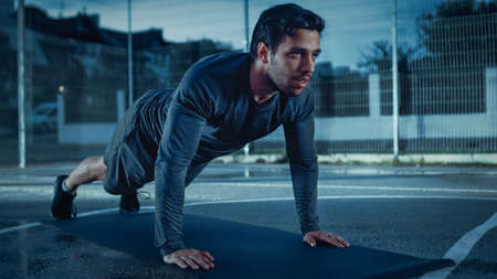Strong Muscular Fit Young Man in Sport Outfit Doing Push Up Exercises. He is Doing a Workout in a...