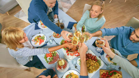Big Family and Friends Celebration at Home, Diverse Group of People Gathered at the Table, Clink Glasses in a Toast. People Eating, Drinking, and Having Fun in the Living Room. Top Down Above Shot.の写真素材