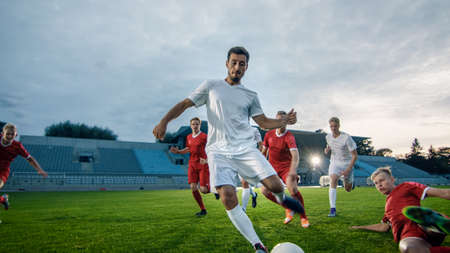 Professional Soccer Player Outruns Members of Opposing Team and Kicks Ball to Score Goal. Soccer Championship on a Stadium.の写真素材