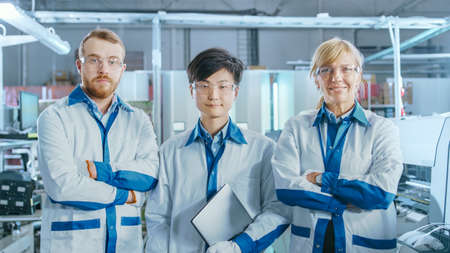On High-Tech Factory: Portrait of Three Professional Engineers Posing with Crossed Arms. In the...
