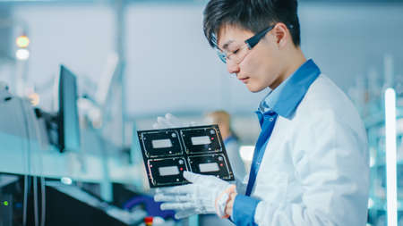 High-Tech Factory: Quality Control Engineer Checks Electronic Printed Circuit Board it for Damages....