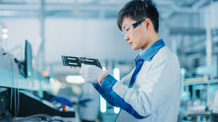 High-Tech Factory: Quality Control Engineer Checks Electronic Printed Circuit Board it for Damages....