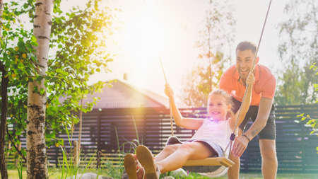 Joyous Father Pushes Swings with His Cute Little Daughter on Them. Happy Family Spends Time Together...