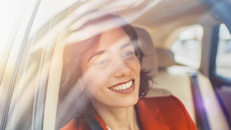 Beautiful Happy Woman Rides on a Passenger Seat of a Car, Looks in Wonder at Big City View. Camera Mounted outside Moving Car.の写真素材