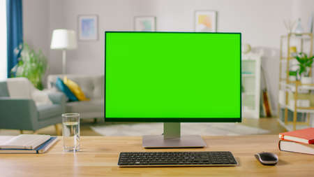 Personal Computer with Mock-up Green Screen Display Standing on the Desk in the Cozy Home Office Living Room of Prominent Designer.の写真素材