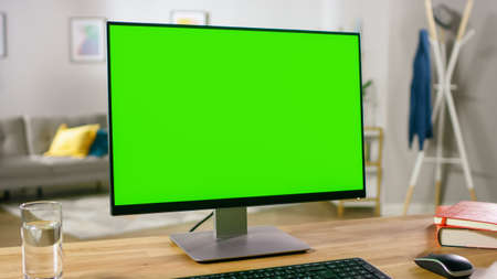 Modern Personal Computer with Mock-up Green Screen Display Standing on the Desk of the Cozy Home Office. Living Room Created by Interior Designer with Good Taste and Style.の写真素材