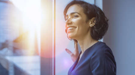 Close-up Portrait of the Beautiful Young Hispanic Woman Looking out of the Window in Wonder. Summertime with Sun Flares in Frame.の写真素材