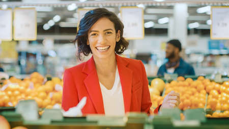 At the Supermarket: Portrait of the Beautiful Smiling into Camera Woman Choosing Products In the...
