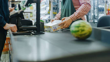 At the Supermarket: Checkout Counter Hands of the Cashier Scans Groceries, Fruits and other Healthy Food Items. Clean Modern Shopping Mall with Friendly Staff, Small Lines and Happy Customers.の写真素材