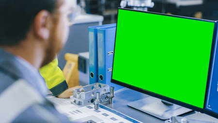 Close-up Back View of the Mechanical Engineer Working on Personal Computer with Green Screen Mock up...