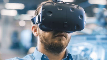 Portrait Shot of the Industrial Engineer Wearing Virtual Reality Headset and Gesturing with...