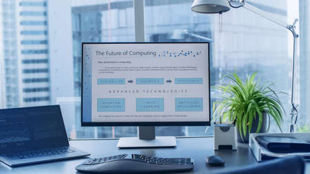Shot of the Office Desk with Personal Computer Standing on It. Future Computing Plans Shown on Monitor. Modern Stylish Room with a Big City Business District View.の写真素材