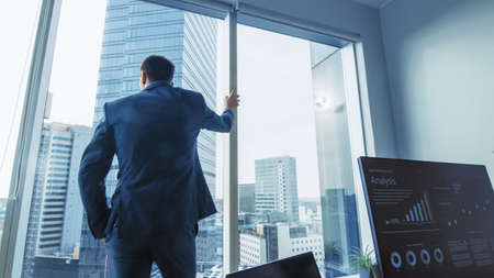 Thoughtful Businessman Wearing Suit Standing in His Office, Looking out of the Window and...