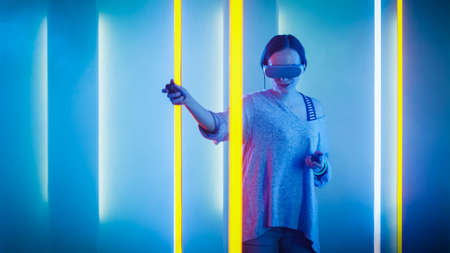 Beautiful Young Girl Wearing Virtual Reality Headset Draws Abstract Lines and Figures with Joysticks...