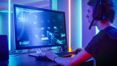 Shot of the Professional Gamer Playing in First-Person Shooter Online Video Game on His Personal...