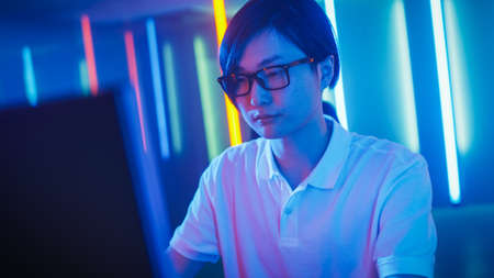 Handsome Young Guy Sits Before Personal Computer, Working, Surfing in Internet and Playing Online...