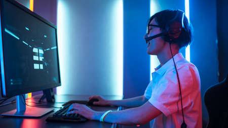Side View Shot of Professional Gamer Playing in First-Person Shooter Online Video Game on His...