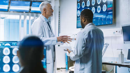 Team of Scientists Work in the Brain Research Laboratory, Discussing Brain Scans Show on Wall TV...