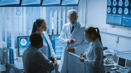 Meeting of the Team of Medical Scientists in the Brain Research Laboratory. Neurologists Neuroscientists Having Analytical Discussion Surrounded by Monitors Showing CT, MRI Scans.の素材 [FY310158096091]