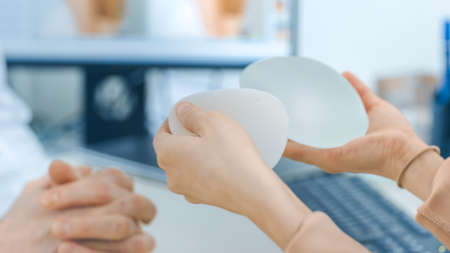 Plastic Cosmetic Surgeon Shows Female Patient Breast Implant Samples for Her Future Surgery....