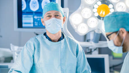 Portrait Shot in the Operating Room, of a Surgeon Looking into Camera During Operation. Professional...