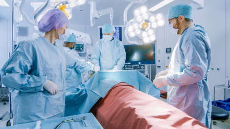 Diverse Team of Professional Surgeons Performing Invasive Surgery on a Patient in the Hospital...