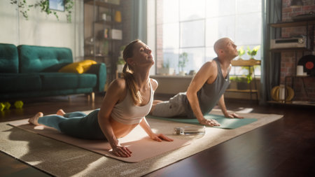 Young Athletic Couple Exercising, Stretching and Practising Yoga in the Morning at Bright and Sunny Home in Loft Living Room. Healthy Lifestyle, Fitness, Wellbeing, Mindfulnessの写真素材