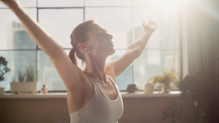 Young Athletic Woman Exercising, Practising Meditation in the Morning in Her Bright Sunny Living Room of Loft Apartment. Healthy Lifestyle, Fitness, Wellbeingの写真素材