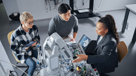 Black Teacher with Laptop and Two Diverse Students Analyse and Discuss Futuristic Robotic Arm During...