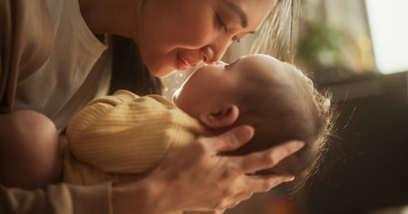 Motherly Affection Concept: Close Up Portrait of an Asian Woman New to Motherhood Having Special Moment with Infant. Cute Baby Smiling and Enjoying Bonding Time Togetherの写真素材