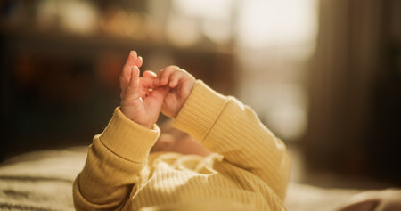 Close-Up on the Hands of a Cute Baby in a Yellow Jumper. Little Active Toddler Trying to Communicate and Cooing. Little Palms Ready to Discover the New World and Receive Love Fromの写真素材