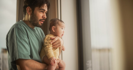 Portrait of Fatherly Love: A Young Father Holding Little Baby in His Arms as He Talks and Watches Through a Window. Man and his Cute Toddler Watching Planes Together.の写真素材