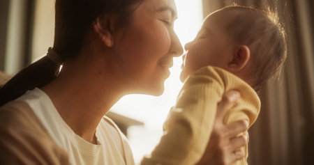 Motherly Affection Concept: Close-Up Portrait of a Cute Asian Baby Laughing and Enjoying Bonding Time Together, Looking at Mother with Love. Woman New to Motherhood Having Specialの写真素材