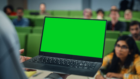 Close Up of an University Professor Using a Laptop Computer with a Green Screen Mock Up Display. Female Teacher Giving a Lecture to a Class of Talented Diverse Youngの写真素材