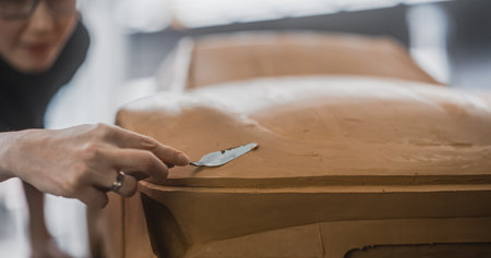 Close Up Portrait of an Automotive Designer Sculpting a 3D Clay Model of a Modern Sustainable...