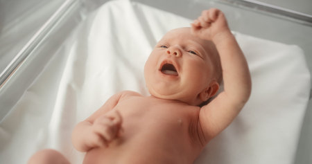 Adorable Caucasian Newborn Child Lying in Hospital Bed in a Nursery Clinic. Little Playful and Healthy Baby. Medical Health Care, Maternityの写真素材