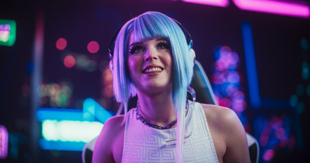 Smiling Cosplay Girl Talking to Her Online Friends on Desktop Computer While Sitting in Futuristic...