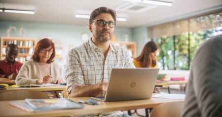 Middle-Aged Man Studying in Classroom, Using Laptop Computer to Write Down Lecture Notes. Group of...