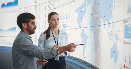 Caucasian Female Regional Manager Talking To Indian Male Distribution Expert In Front Of Big Digital...