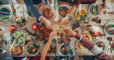 Family and Friends Gather at Home for a Traditional Christmas Dinner with a Turkey Roast Feast. Top Down View on People Raising Champagne Glasses and Toasting, Celebratingの写真素材