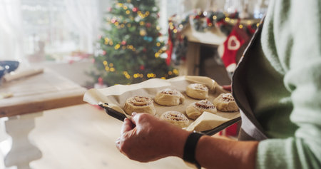 Close Up of a Senior Female Preparing Making Cinnamon Buns for Christmas at Home. Cheerful Housewife and Grandmother Making Pastries to Share with Family and Friendsの写真素材