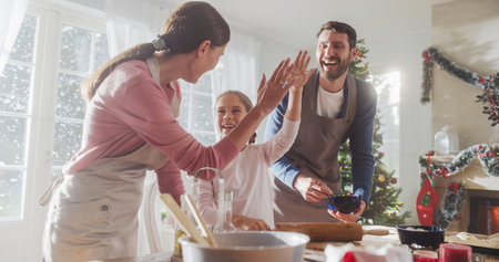 Happy Family During Christmas: Portrait of Little Cute Girl Learning How to Make Cookies and Celebrating her Achievement with her Parents. Cute Family Preparing Togetherの写真素材